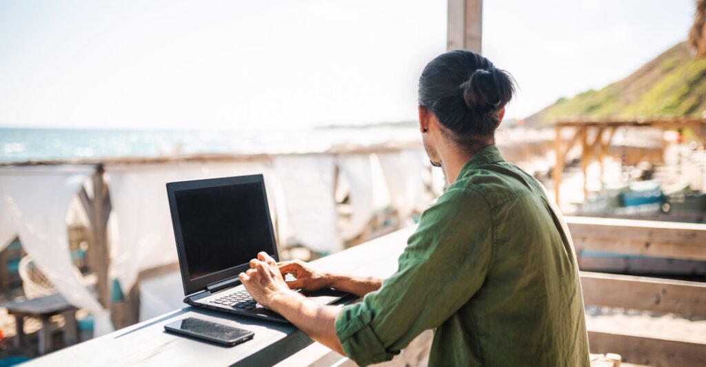 Remote worker using a laptop in a scenic location, embracing creative freedom.