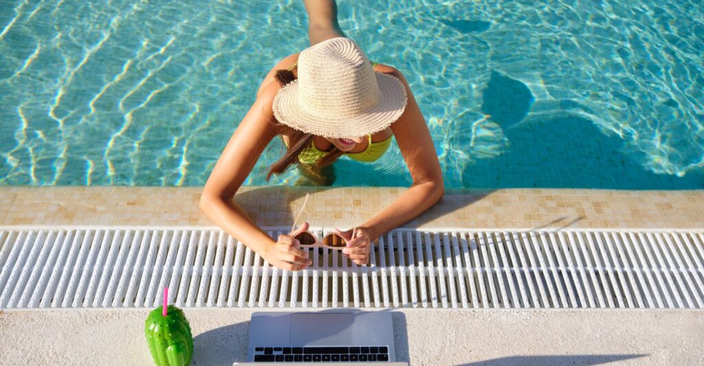 Digital nomad relaxing in a pool with laptop nearby, symbolizing freedom through passive income